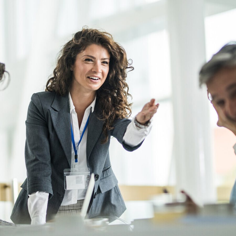 Happy female CEO communicating with her colleagues on a meeting in the office.